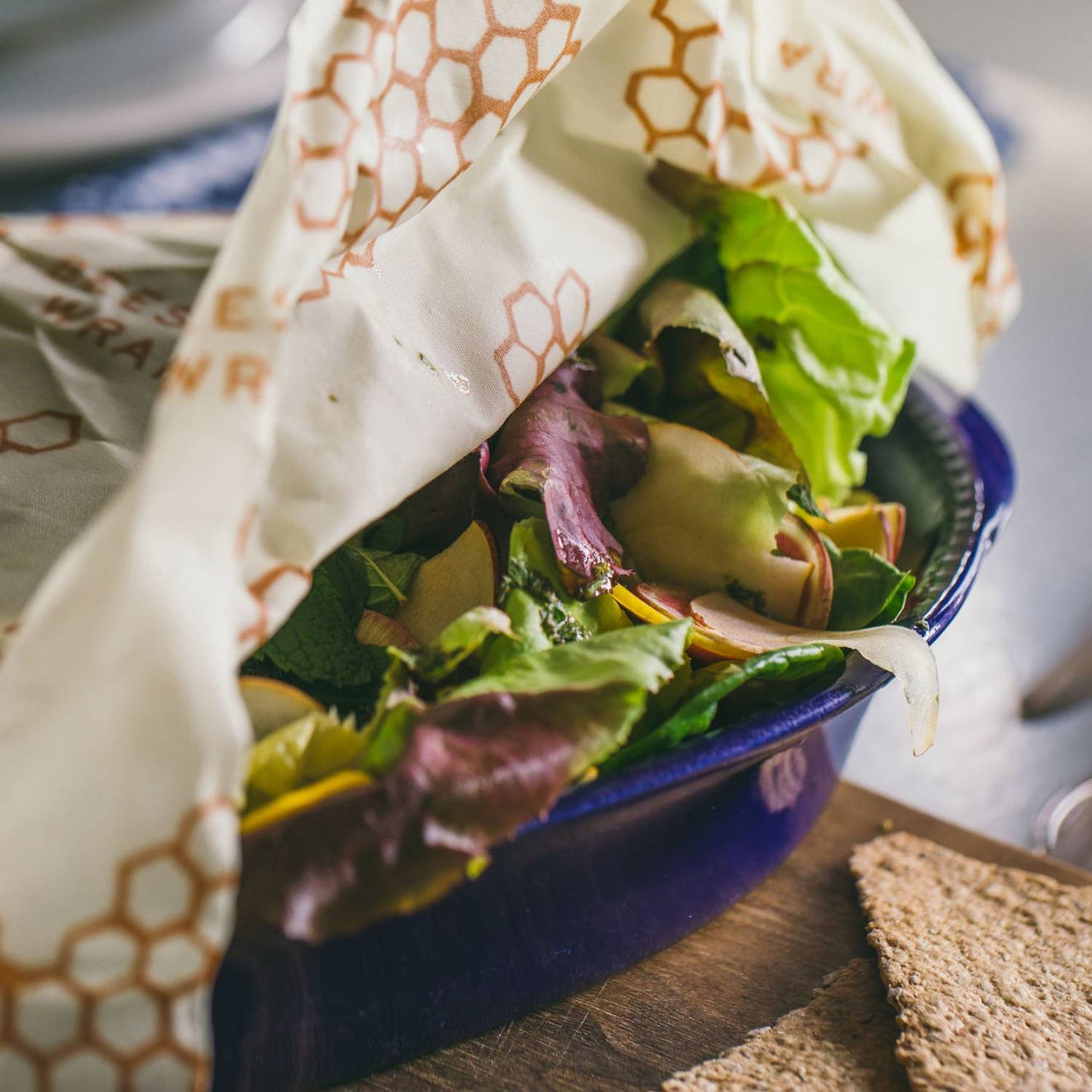 Handcrafted large beeswax food wrap with honeycomb pattern partially covering fresh mixed salad in a blue ceramic bowl, ideal for Kitchen & Food, Storage and Serving, USA Made, and Best Sellers collections.