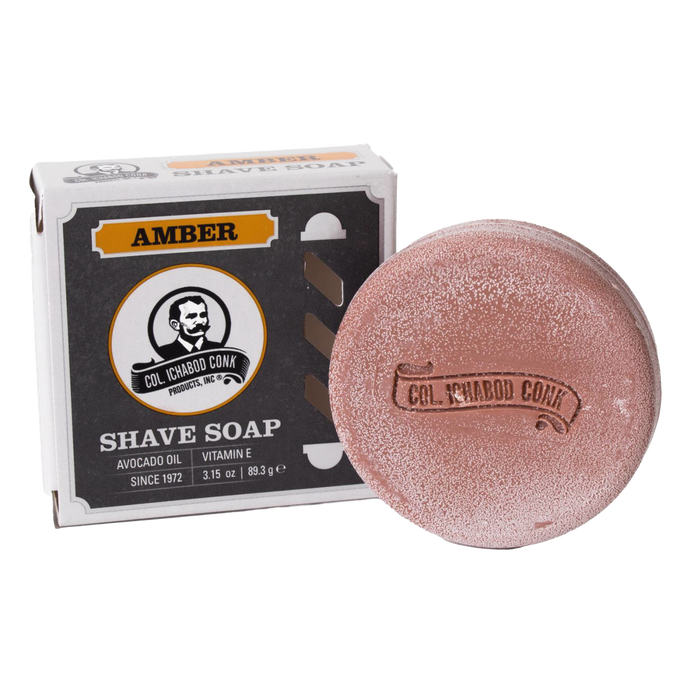 Amber-colored shaving soap puck with embossed branding alongside its box featuring vintage design, containing avocado oil and vitamin E, ideal for Health & Wellness and Grooming collections.