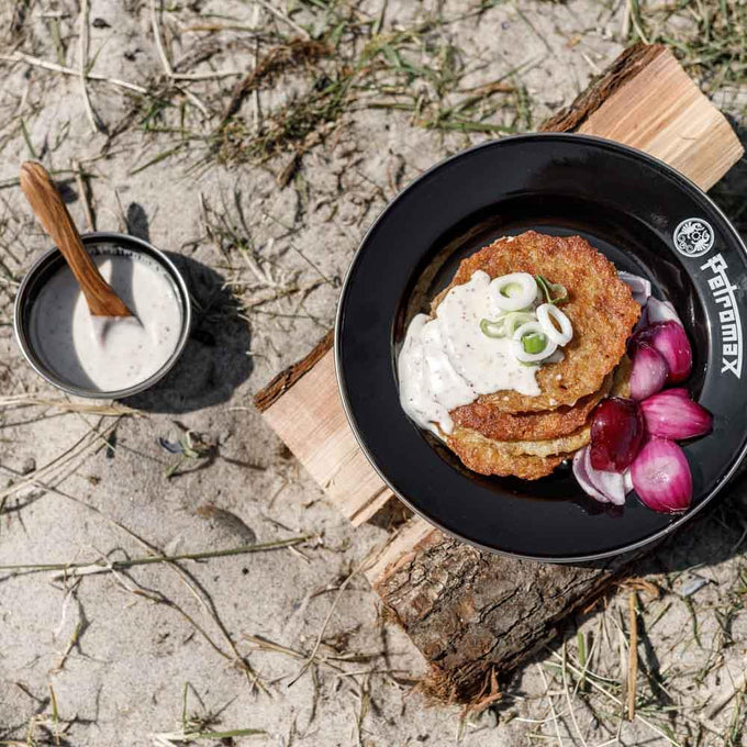 Black enamel bowl with crisp potato pancakes topped with creamy sauce and sliced green onions, accompanied by pickled red onions and a small black enamel cup with sauce and wooden spoon, perfect for outdoor dining in Farm, Garden & Tool, Kitchen & Food, Camping, Dinnerware, Best Sellers, and Promo Eligible collections.