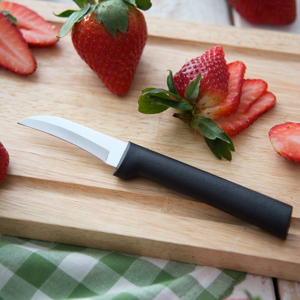 Curved hand-sharpened stainless steel paring knife with a black handle resting on a wooden cutting board beside sliced and whole fresh strawberries, handcrafted and made in USA, featured in Farm, Garden & Tool and Kitchen & Food collections.