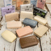 Variety of handcrafted soap bars in natural tones arranged on rustic wooden surface, part of a USA made grooming and personal hygiene collection.