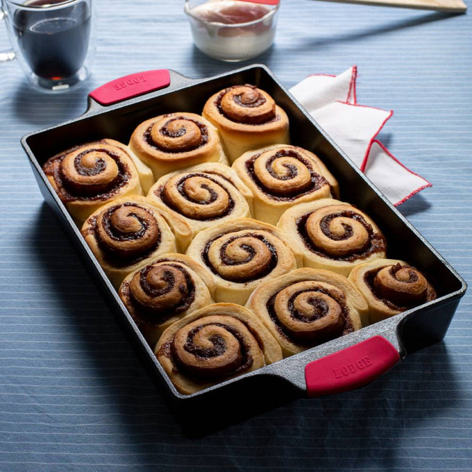 Handcrafted cast iron casserole pan with dual red silicone grips, filled with freshly baked cinnamon rolls, ideal for Kitchen & Food, Cookware, Cast Iron, USA Made, Best Sellers, Promo Eligible collections.