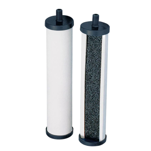 Two cylindrical replacement filtration elements for tabletop water filters, featuring black end caps and a white outer surface with one open side revealing granular filtering material inside.