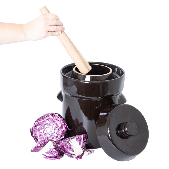 Glossy black stoneware crock with matching lid and wooden stomper in use, shown alongside fresh cut purple cabbage, handcrafted and ideal for Kitchen & Food, Food Preservation, Fermenting and Pickling, Best Sellers, and Promo Eligible collections.