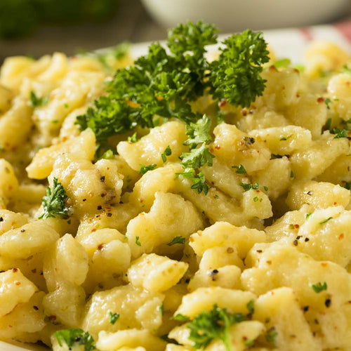 Close-up of freshly cooked spaetzle noodles seasoned with herbs and black pepper, garnished with sprigs of fresh parsley, perfect for Kitchen & Food and Best Sellers collections.