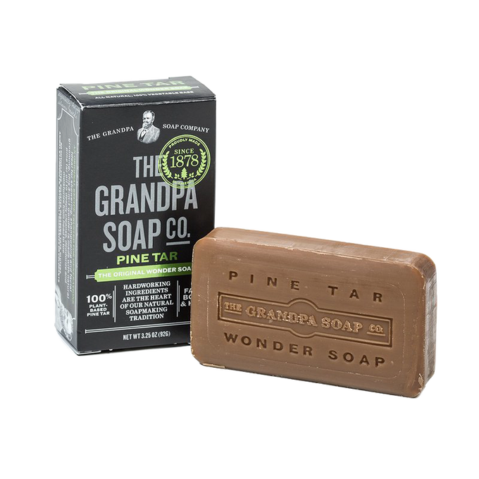 Bar of pine tar soap with embossed branding beside its black and green box, handcrafted and made in USA, featured in Health & Wellness, Grooming and Personal Hygiene, and Best Sellers collections.