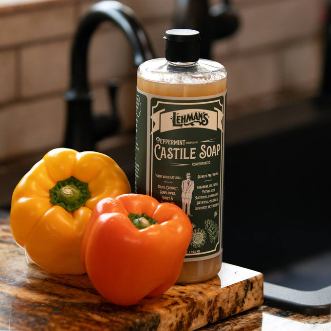 Handcrafted amber bottle of Lehman's peppermint castile soap placed on wooden cutting board beside yellow and orange bell peppers, highlighting natural USA made soap in Health & Wellness and Grooming collections.
