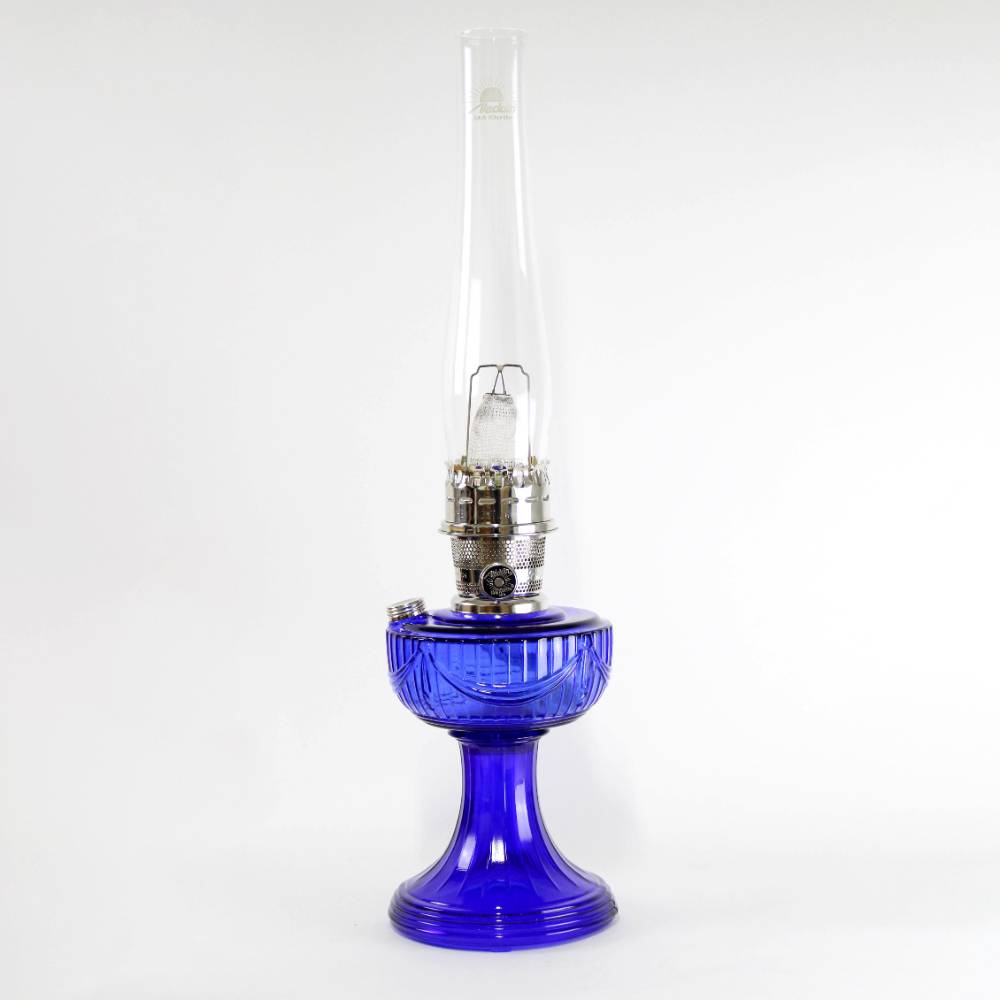 Handcrafted cobalt glass oil lamp with sweeping font design, brass burner, and tall clear chimney, ideal for Lamps & Lighting, Oil Lamps, Table Lamps, Best Sellers, and Promo Eligible collections.