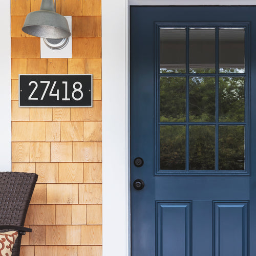 Handcrafted modern black and silver address plaque with white numbers, made in USA, mounted on wood-shingled exterior by blue paneled glass door, enhancing curb appeal in Home & Decor, Household Helpers, Mailboxes and Address Signs, USA Made, Best Sellers, and Promo Eligible collections.