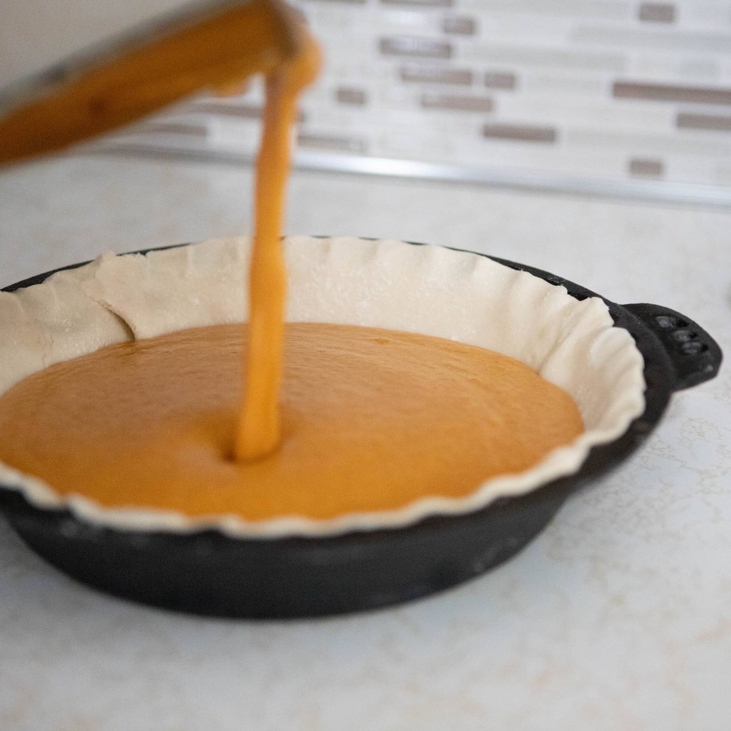 Handcrafted cast iron pie pan with crimped edges, shown being filled with pumpkin pie batter, perfect for Kitchen & Food, Cookware, Cast Iron, Baking Supplies, Best Sellers, and Promo Eligible collections.
