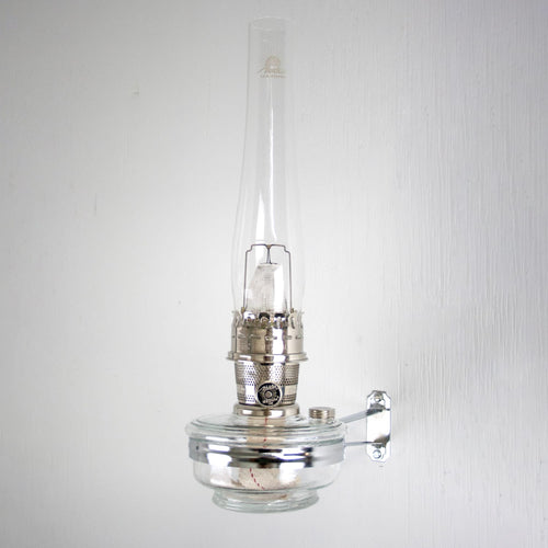 Handcrafted clear wall-mounted oil lamp with a polished metal burner and tall glass chimney, designed for space-saving lighting in Farm, Garden & Tool, and Lamps & Lighting collections.
