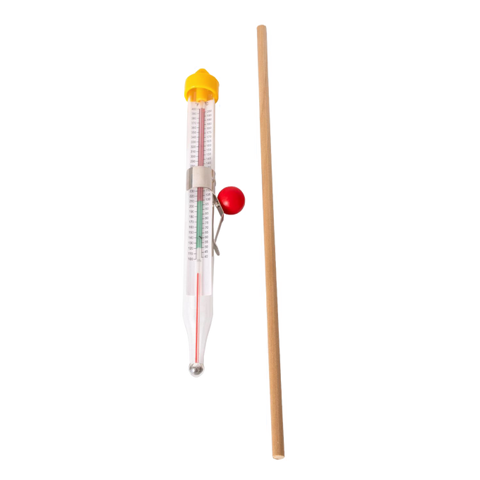 Glass candle thermometer with metal clip and red pointer alongside a wooden stirring stick, essential tools in candlemaking supplies for precise temperature control and mixing in Lamps & Lighting and Candlemaking collections.