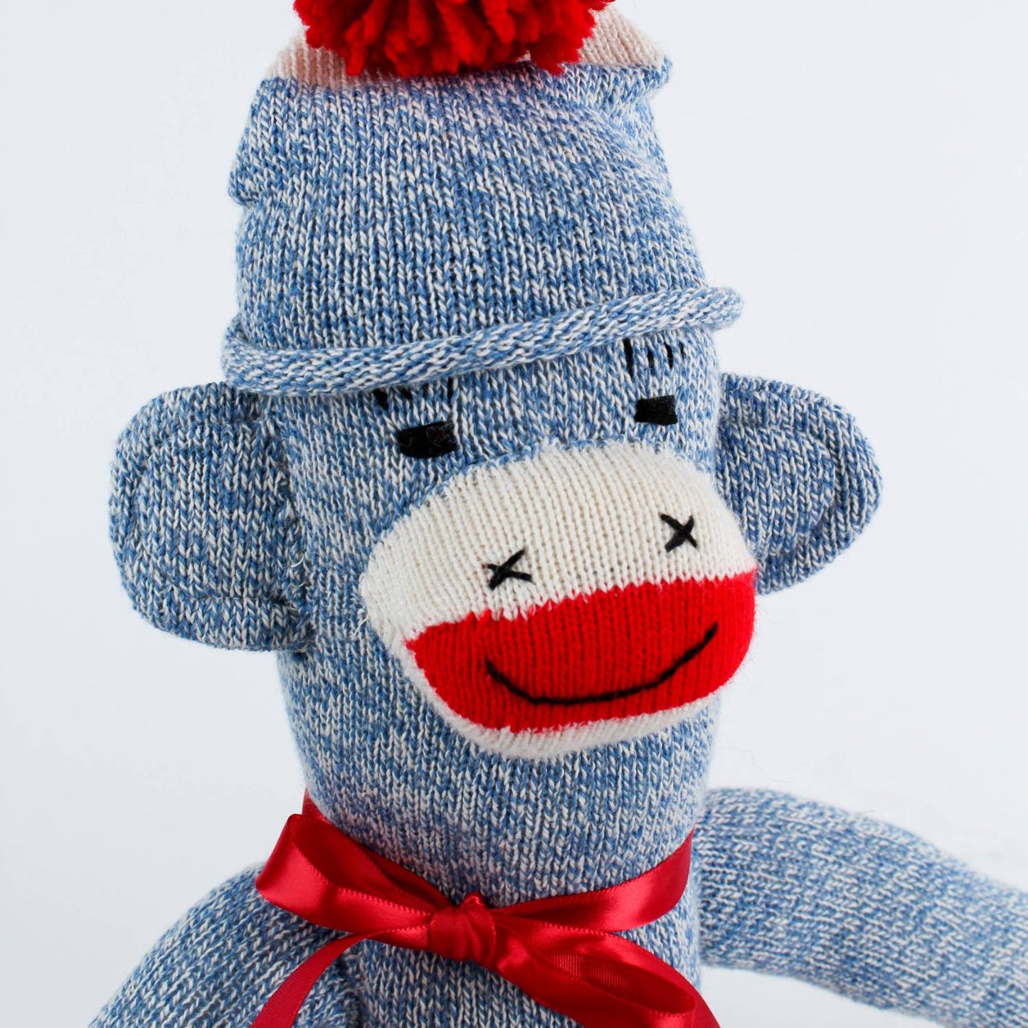 Hand-sewn classic sock monkey in blue and white knit with a red pom-pom hat and red ribbon bow, handcrafted in the USA, featured in Toys, Books & Games, Children's Toys, and Best Sellers collections.
