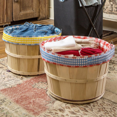 Handcrafted reusable liners with colorful gingham patterns slip over wooden bushel baskets to protect and carry laundry, ideal for Home & Decor and Laundry Supplies collections.