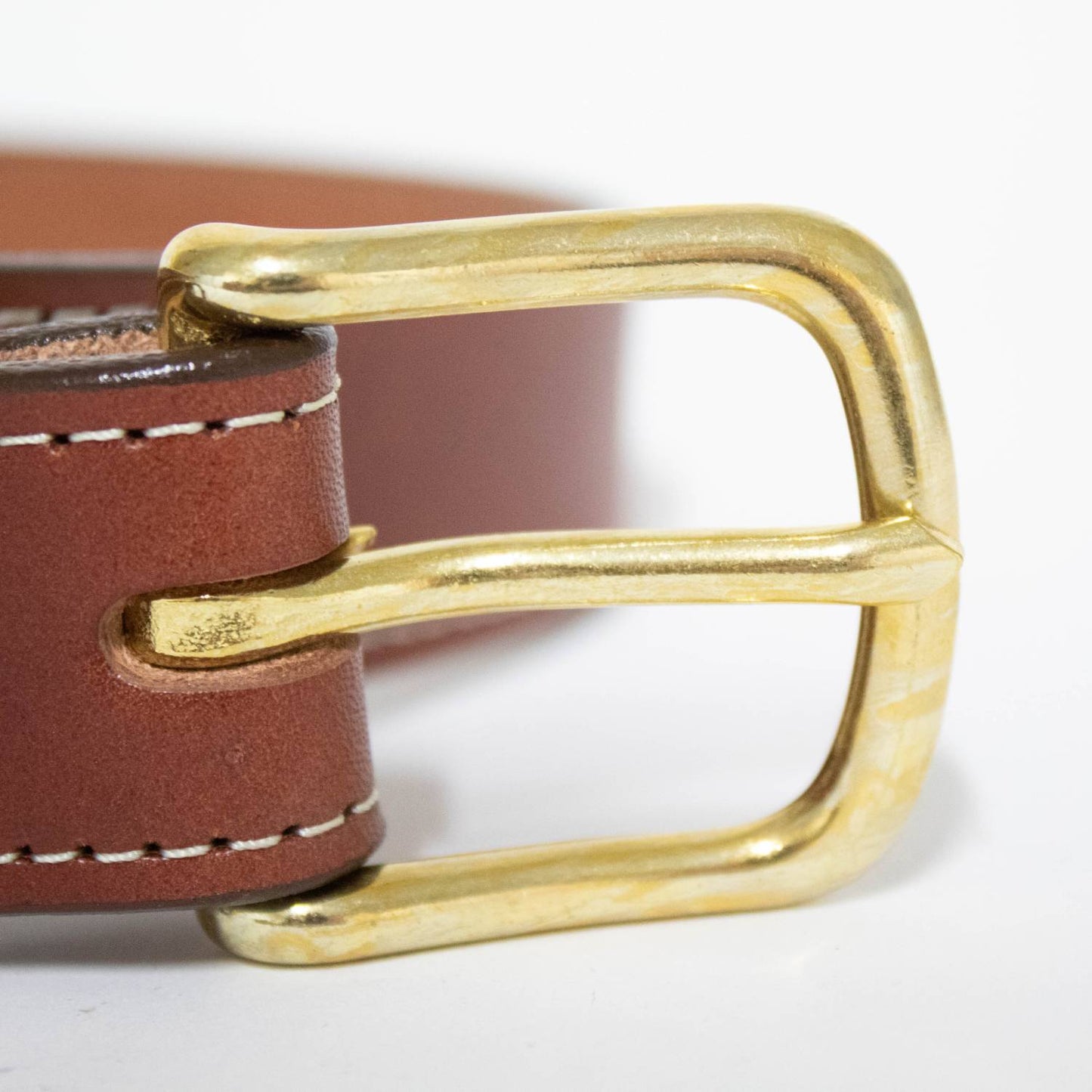 Close-up of a handcrafted Amish-made brown genuine English bridle leather belt with a polished brass buckle, featuring fine stitching, part of USA Made and Best Sellers collections.