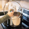 Handcrafted polished stainless steel water bath canner with clear lid and pressure gauge, shown on a stove in a kitchen setting, ideal for Food Preservation and Kitchen & Food collections.