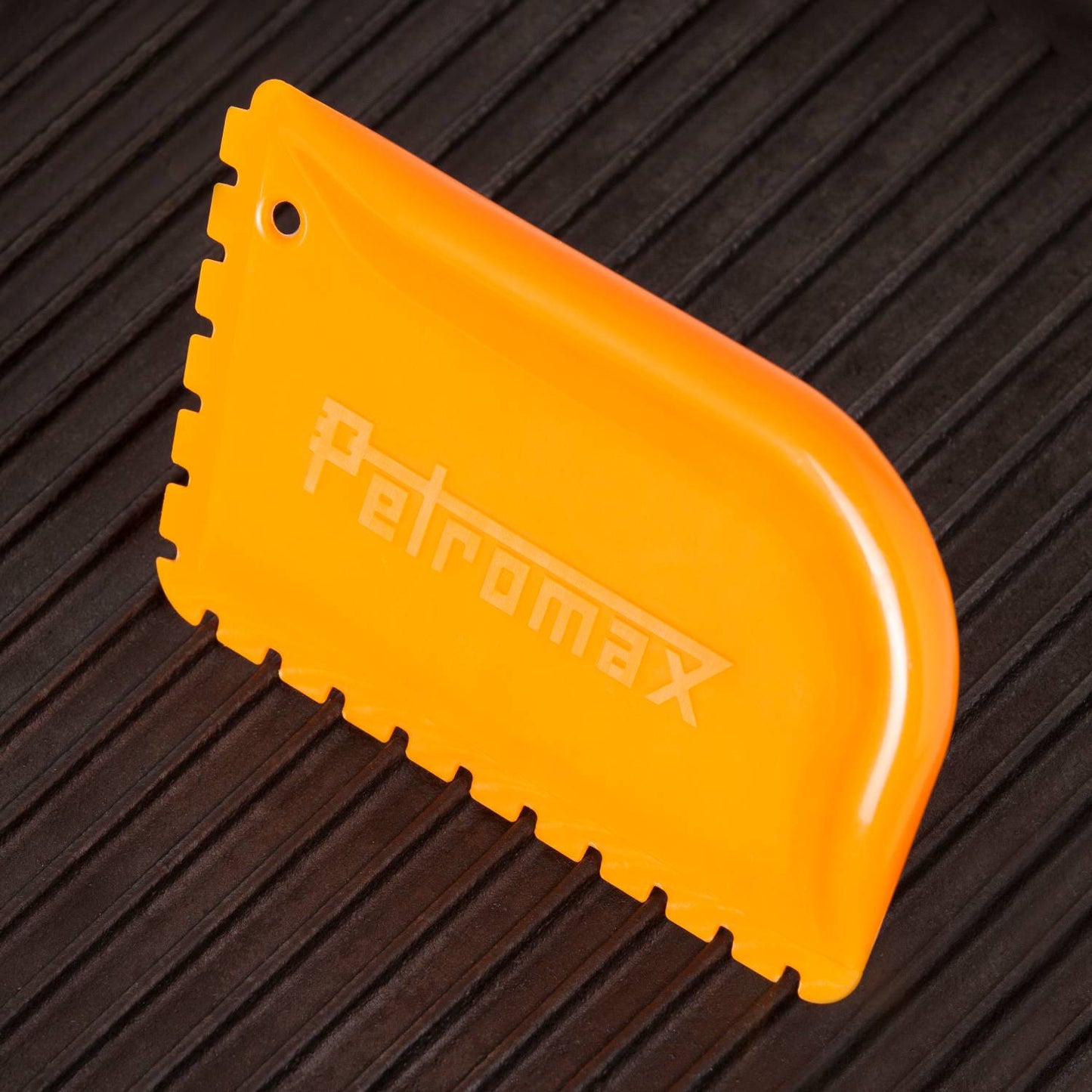 Bright orange pan scraper with serrated edges designed for cleaning cast iron cookware, featured in Kitchen & Food, Cookware, Cast Iron, and Best Sellers collections.