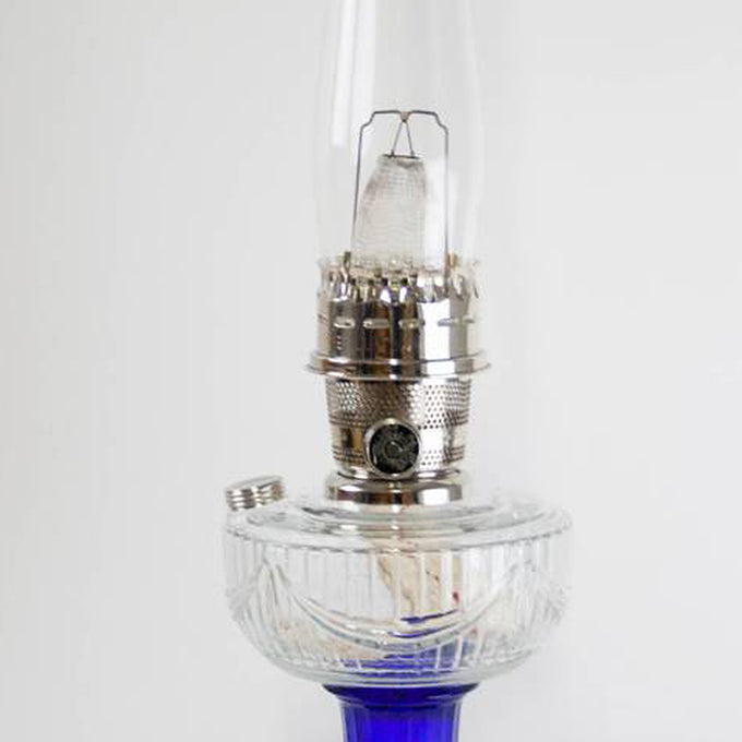 Handcrafted oil lamp featuring a silver nickel burner with a clear glass font showcasing a sweeping drape design above a deep cobalt blue base, ideal for Lamps & Lighting, Oil Lamps, Table Lamps, Best Sellers, and Promo Eligible collections.