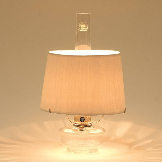 Clear glass oil lamp with bright warm light, featuring a white parchment shade and tripod, ideal for farm, garden, emergency supplies, and table lamp collections.