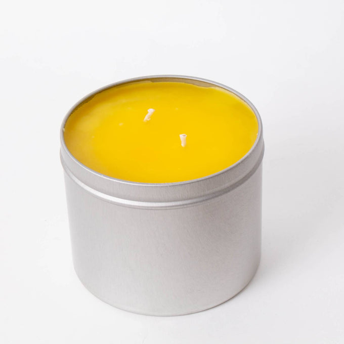 Hand-poured Amish-made citronella candle with two wicks and bright yellow wax in a compact lightweight metal tin, perfect for camping, pest control, and outdoor lighting.