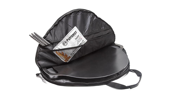 Black round transport bag with spacious interior, mesh pocket, and durable handles, designed for secure packing of griddles and fire bowls, perfect for camping, farm, and garden use.