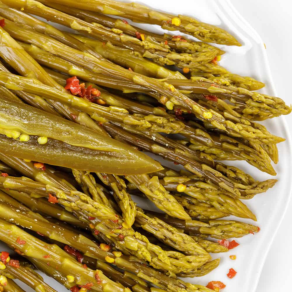 Close-up of handcrafted pickled asparagus spears seasoned with red pepper flakes, showcasing a tangy, spicy flavor, ideal for Kitchen & Food, Food, Pantry, USA Made, and Best Sellers collections.