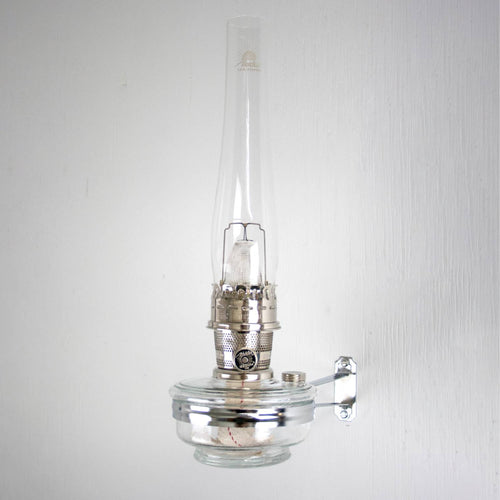 Handcrafted clear glass oil lamp with polished metal burner and wall-mounted bracket, designed for classic Aladdin lamps, featured in Lamps & Lighting, Oil Lamps, Wall Lamps, Best Sellers, and Promo Eligible collections.