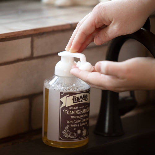 Hand pressing the pump of handcrafted Lehman's foaming hand soap with natural moisturizing oils including olive, coconut, and jojoba, made in USA, featured in Health & Wellness and Soaps collections.