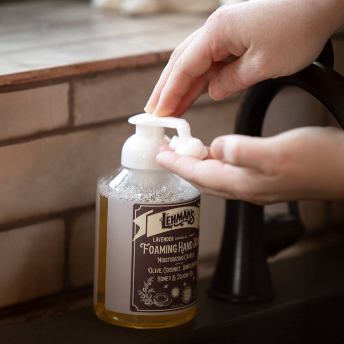 Hand pressing the pump of handcrafted Lehman's foaming hand soap with natural moisturizing oils including olive, coconut, and jojoba, made in USA, featured in Health & Wellness and Soaps collections.