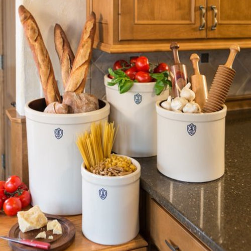 Set of handcrafted 3-gallon and smaller numbered stoneware crocks made in USA, styled on a kitchen counter with bread, pasta, fresh tomatoes, garlic, and utensils, ideal for Kitchen & Food, Food Preservation, Fermenting and Pickling, Best Sellers, and Promo Eligible collections.