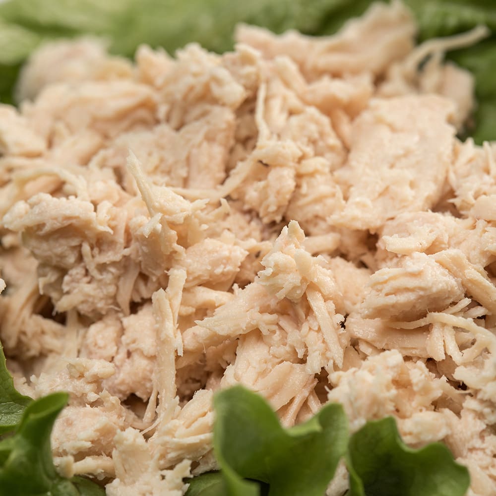 Close-up of shredded, fully cooked chicken resting on fresh green lettuce, highlighting a convenient meal option featured in Kitchen & Food, Food, Meats, Best Sellers, and Promo Eligible collections.
