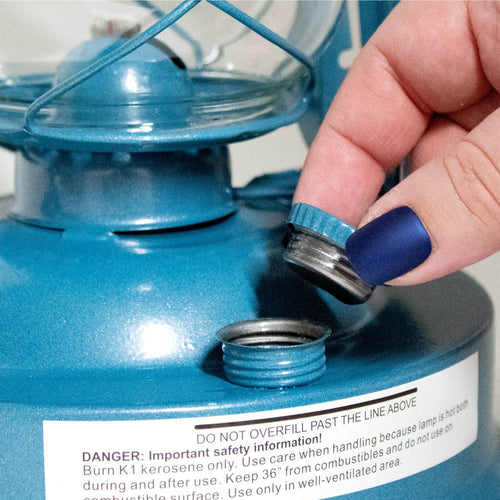 Close-up of a hand removing the metal fuel cap from a blue handcrafted lantern, featured in Farm, Garden & Tool, Lamps & Lighting, Camping, Emergency Supplies, Best Sellers, and Promo Eligible collections.