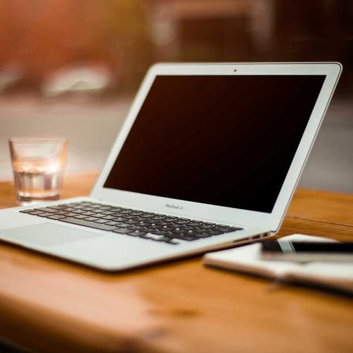Laptop with blank screen on wooden table next to smartphone and glass of water, capturing a warm, inviting workspace atmosphere for Best Sellers and P3 Testing collections.