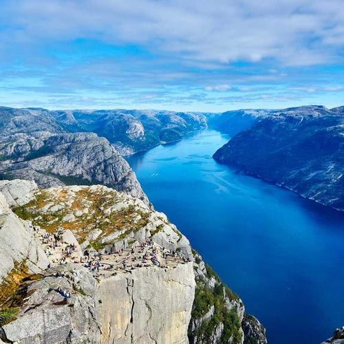 A panoramic view of a deep blue fjord surrounded by rugged cliffs and rocky terrain under a partly cloudy sky, conveying natural beauty and outdoor adventure, featured in Best Sellers and P3 Testing collections.