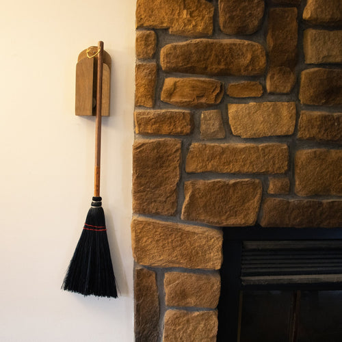 Handcrafted Amish made wooden wall-mount broom holder in natural finish, mounted beside a rustic stone fireplace, perfect for Home & Decor and Household Helpers collections.