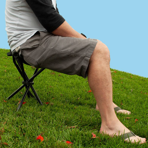Person seated on a lightweight four-legged folding stool with black metal frame on grass, designed for camping and outdoor activities, featured in Farm, Garden & Tool, Camping, Best Sellers, Promo Eligible, and Sale collections.