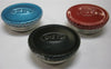 Three round metal filler caps in black, blue, and red finishes, each embossed with a brand name, suitable for use with camping lamps and emergency lighting supplies.