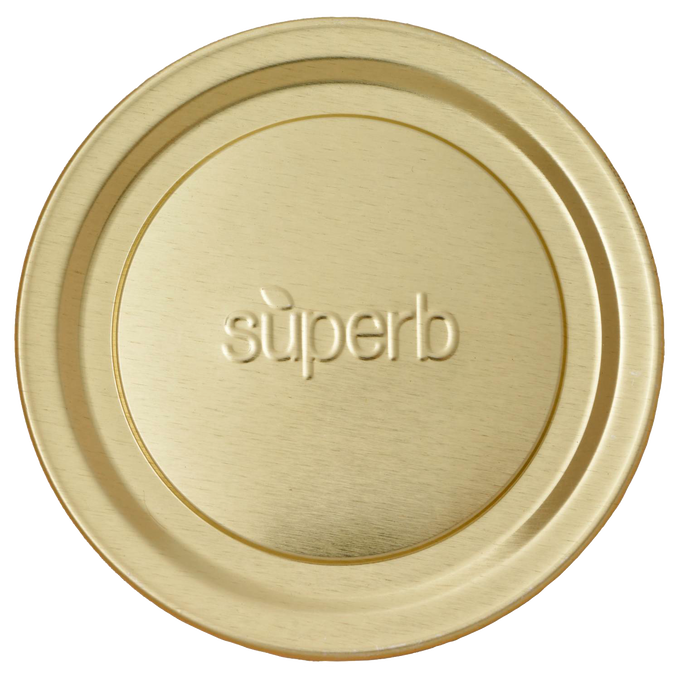 Close-up of a wide mouth, gold-tone canning jar lid embossed with the word superb, designed for secure sealing in food preservation and kitchen use, made in USA.