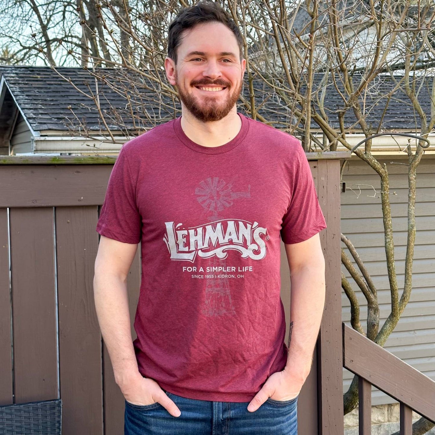 Man wearing a soft, lightweight maroon t-shirt featuring a faded windmill graphic and "Lehman's For a Simpler Life" print, perfect for Health & Wellness and Clothing collections.