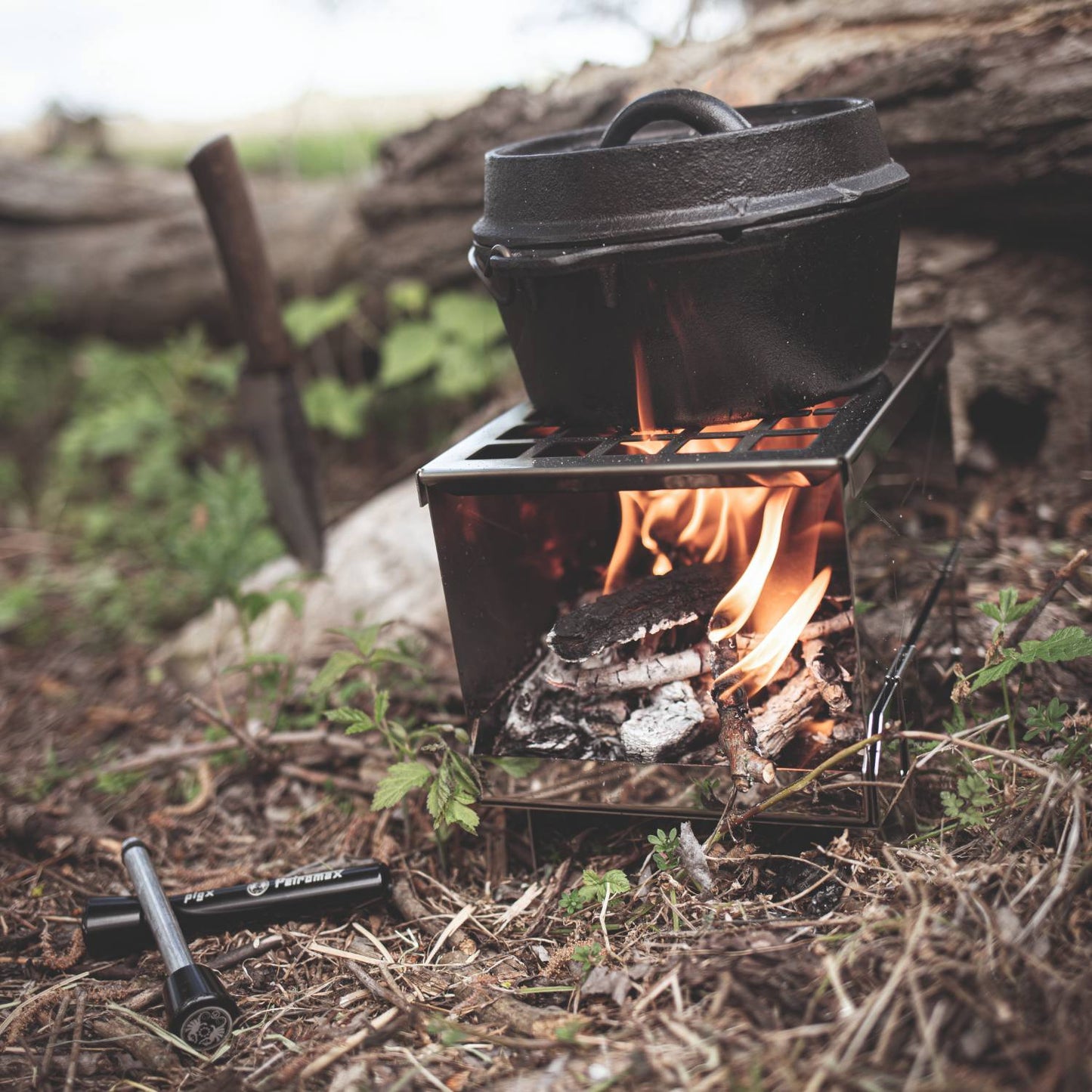 Handcrafted compact camp stove burning wood in a stainless steel firebox with a cast iron pot cooking over the flame, ideal for Farm, Garden & Tool, Camping, Emergency Supplies, Best Sellers, and Promo Eligible collections.