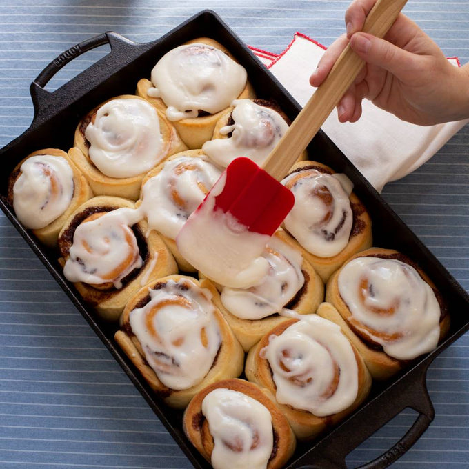 Handcrafted cast iron casserole pan with dual handles, filled with freshly baked cinnamon rolls being spread with creamy icing, featured in Kitchen & Food, Cookware, Cast Iron, USA Made, Best Sellers, and Promo Eligible collections.