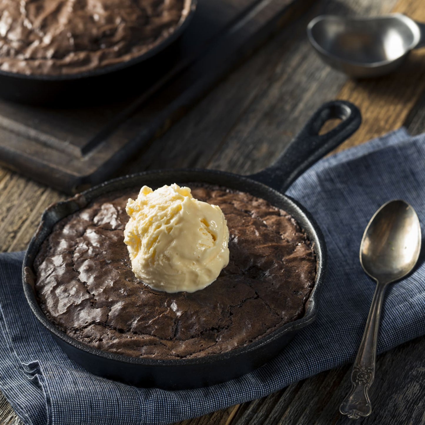 Handcrafted rich chocolate dessert baked in a 6-inch cast iron skillet topped with a scoop of creamy vanilla ice cream, styled on rustic wood with vintage spoon in Kitchen & Food, Dry Goods and Mixes, Best Sellers collection.