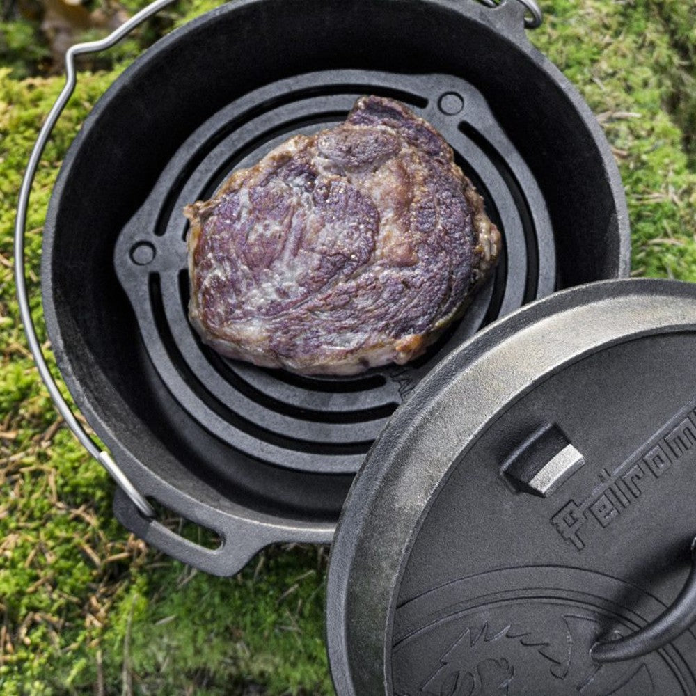 Heavily seared steak cooking on a sturdy cast iron stack grate inside a Dutch oven, showcasing durable construction and excellent heat control for camping and kitchen use in Farm, Garden & Tool, Kitchen & Food, Camping, Cookware, and Cast Iron collections.