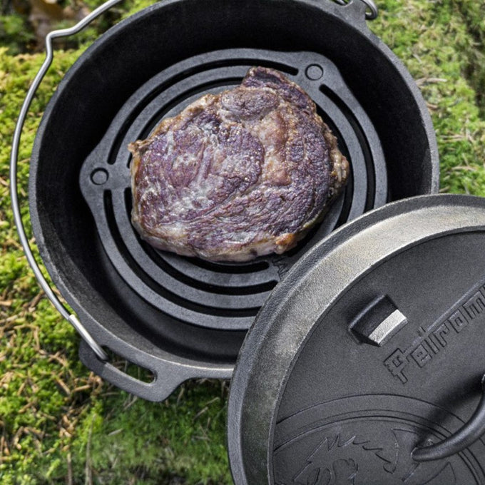 Heavily seared steak cooking on a sturdy cast iron stack grate inside a Dutch oven, showcasing durable construction and excellent heat control for camping and kitchen use in Farm, Garden & Tool, Kitchen & Food, Camping, Cookware, and Cast Iron collections.