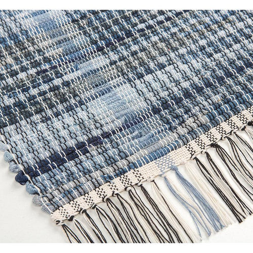 Close-up of a handcrafted woven denim rug in varying shades of blue with a textured pattern and fringed edge, featured in Home & Decor, Home Textiles, USA Made, and Best Sellers collections.