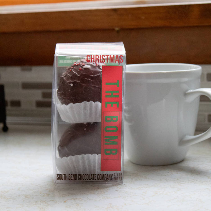 Clear packaging showing handcrafted chocolate bombs with festive crushed peppermint candy atop, placed beside a white ceramic mug, perfect for Kitchen & Food, Snacks and Sweets, Beverages, USA Made, Best Sellers, and Promo Eligible collections.