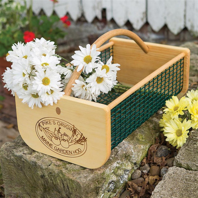 Handcrafted wooden garden hod with green wire mesh sides and curved handle, featuring an engraved logo, holding a bouquet of white daisies, part of Farm, Garden & Tool and USA Made collections.