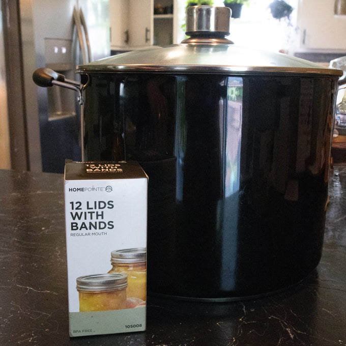 Box of 12 regular-mouth canning lids and bands with BPA-free sealing compound displayed beside a large black cooking pot, ideal for Kitchen & Food and Food Preservation collections.