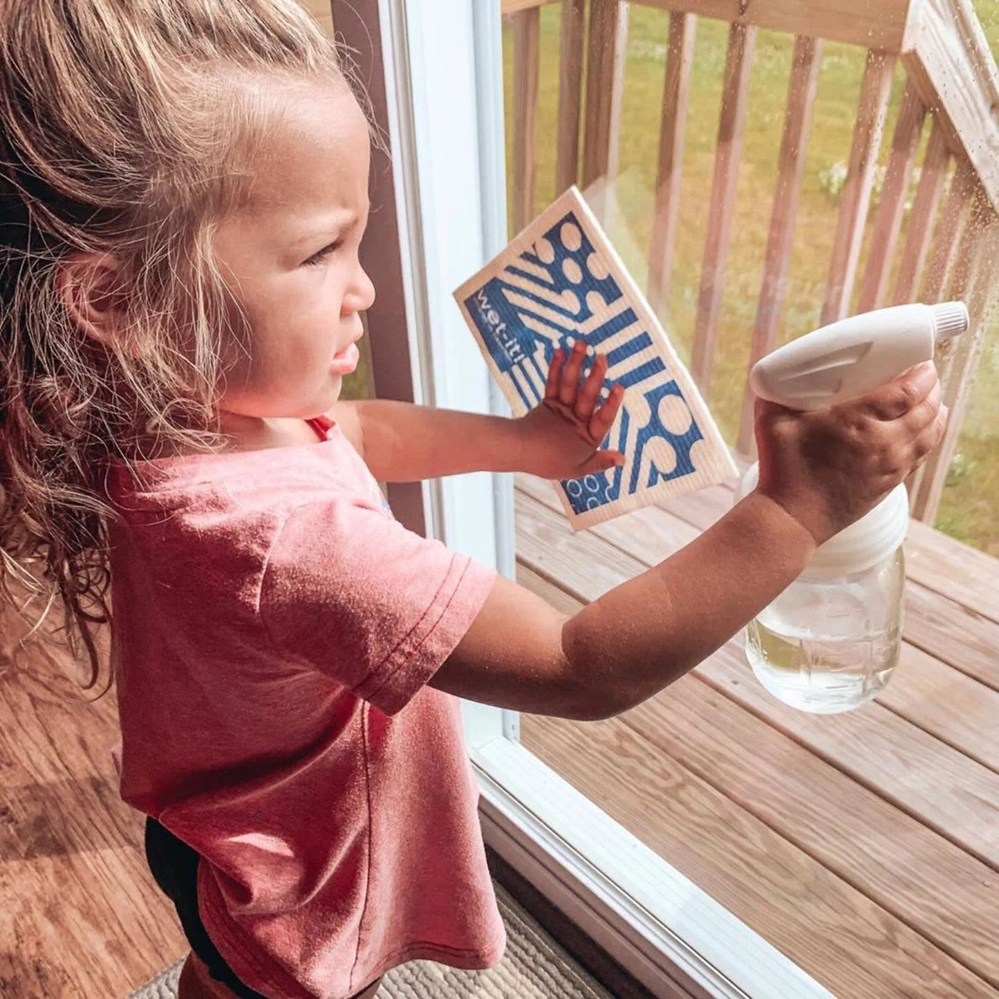 Child using a clear regular-mouth glass jar with a white sprayer lid to clean a window, demonstrating eco-friendly home cleaning tools from Home & Decor, Household Helpers, USA Made collections.