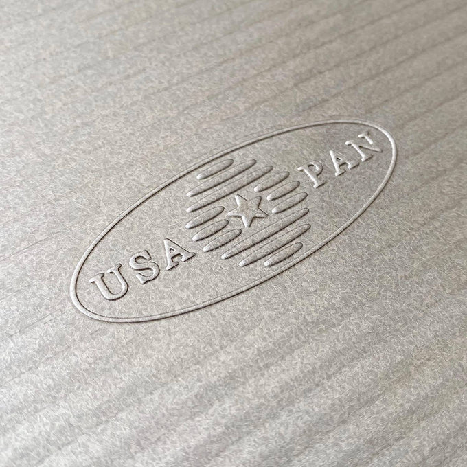 Close-up of an embossed USA Pan logo on a nonstick aluminized steel surface, highlighting handcrafted American craftsmanship in Kitchen & Food, Cookware, and Baking Supplies collections.